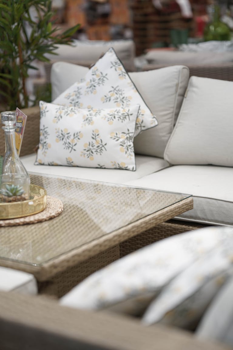 Cozy outdoor seating with floral cushions and a glass table, perfect for relaxation.